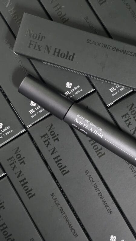 BL Lashes Noir Fix N Hold black tint enhancer tube displayed on top of multiple matching black product boxes.