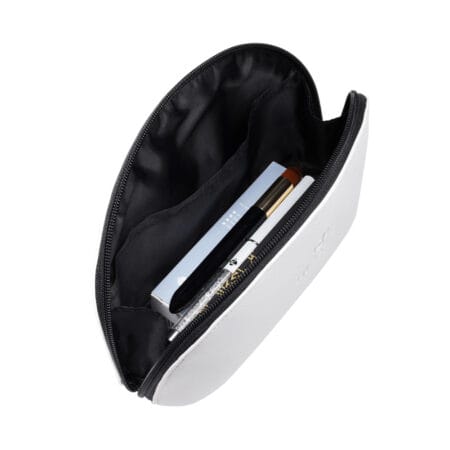 Open white zippered beauty pouch with black lining, containing professional lash and beauty tools including a brush, pen and boxed products.
