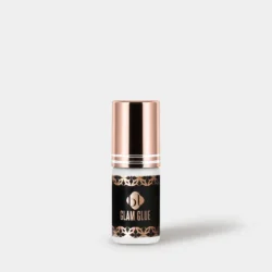 Glam Glue_5g_grey BL Lashes Glam Glue eyelash extension adhesive in a 5 g black bottle with a rose-gold cap on a light grey background.
