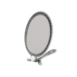 Ornate oval silver tabletop mirror with a decorative vintage-style frame and folding stand on a white background.