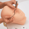 Lash artist practising eyelash extension application with precision tweezers on a realistic mannequin training head.