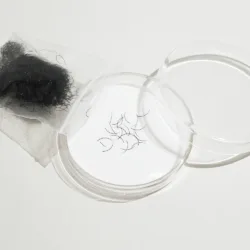 Loose mink eyelash extensions in a clear storage container with additional lash fibres in a small transparent bag.
