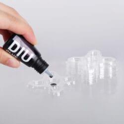 PLASTIC GLUE TRAY_How to Use Eyelash extension glue being dispensed from a bottle into a clear plastic multi-well glue tray for professional lash application.