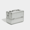 Silver professional beauty case with a textured studded finish, reinforced metal corners, chrome hardware, and a carry handle on a light background.