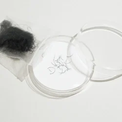 Loose black mink eyelash extensions displayed beside an open clear container and a bulk pouch on a white background.